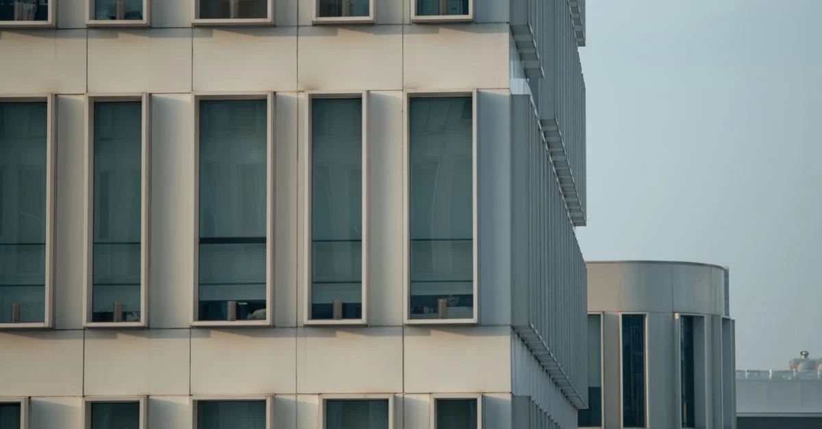 Vue rapprochée de la façade d'un bâtiment de bureaux moderne mettant en valeur un design géométrique avec des fenêtres verticales.