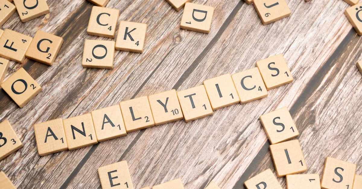 Lettres de scrabble formant 'Analytics' sur une surface en bois, symbolisant le concept d'analyse de données.