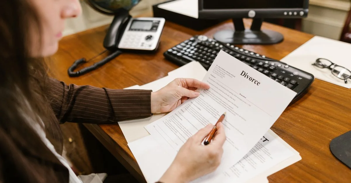Une avocate examine des documents de divorce à un bureau dans un cadre de cabinet d'avocats, mettant en avant le professionnalisme.