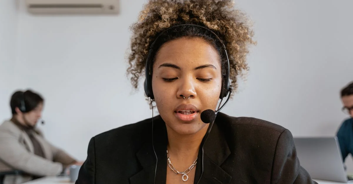 Agent de support client concentré avec un casque, travaillant dans un environnement de bureau.