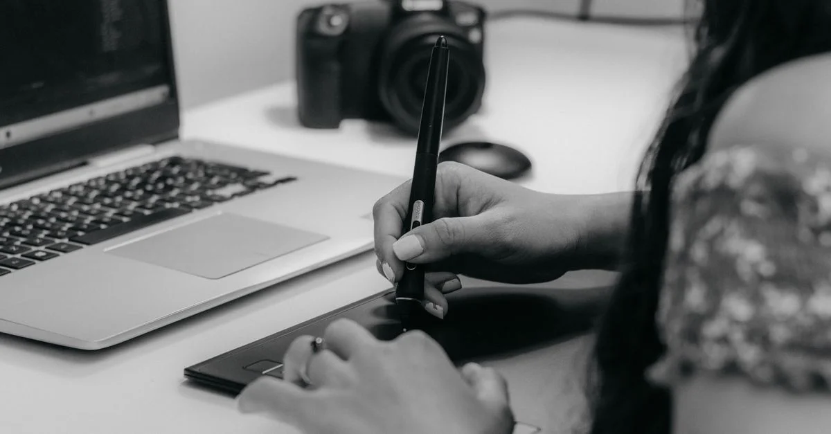 Un designer travaillant avec une tablette graphique et un ordinateur portable, soulignant la créativité numérique moderne.