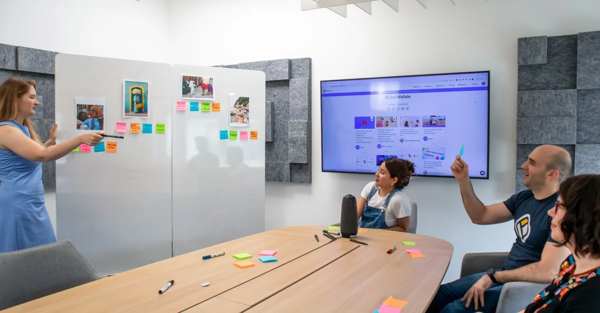 Un groupe de collègues engagé dans une séance de brainstorming créatif avec des notes Post-it colorées et un affichage numérique.