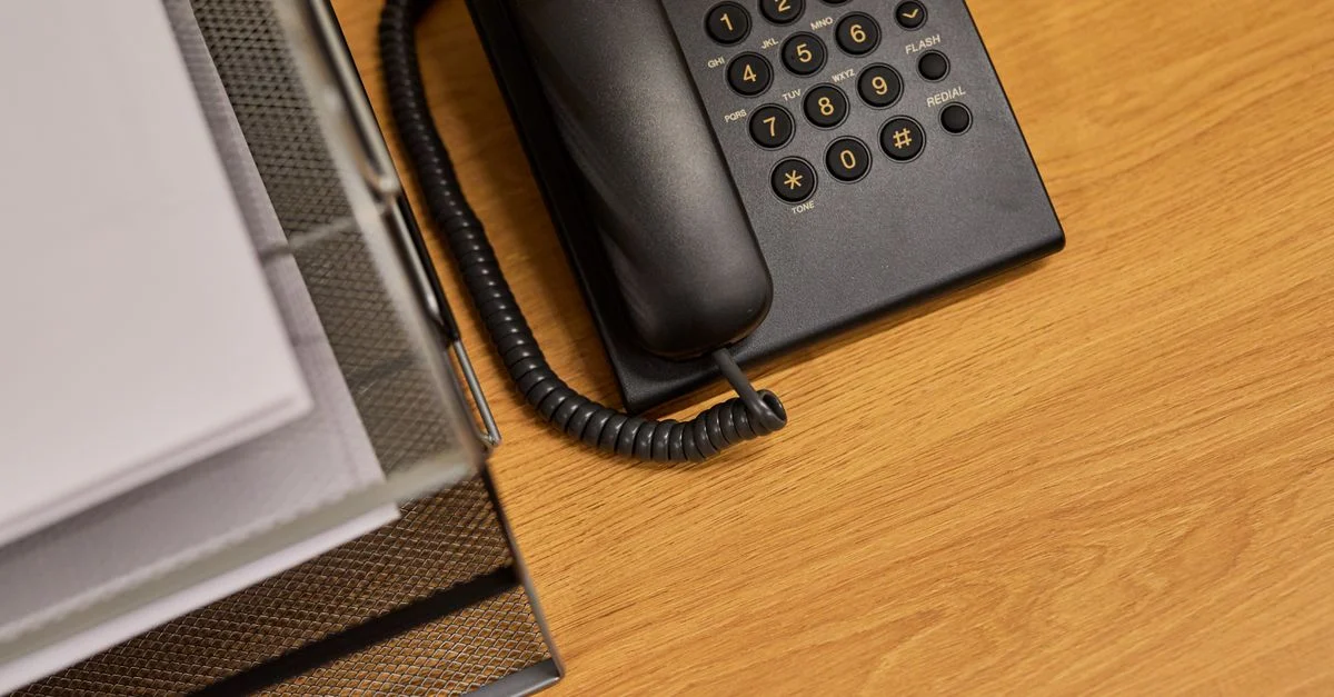 Un bureau de bureau en ordre avec un téléphone noir classique et des documents organisés.